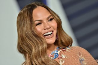 Chrissy Teigen Channels Cher’s ’90s Workout Videos For ‘The Best 38 Minutes of Fat-Burning Fun’
