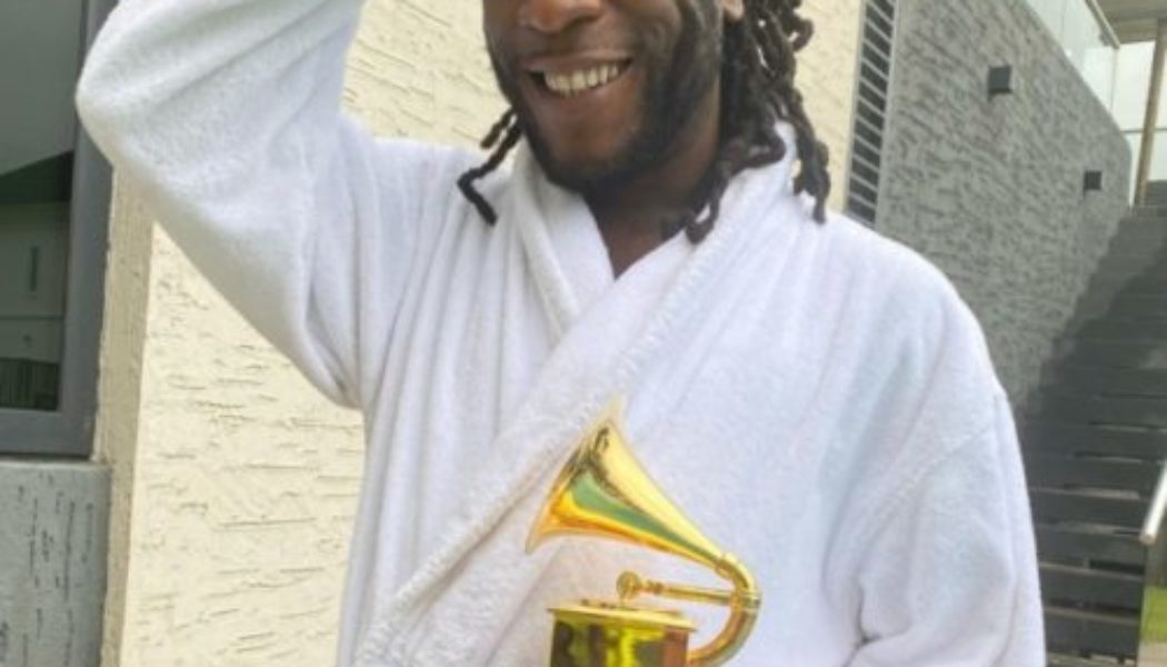 Burna Boy drinks champagne out of his Grammy plaque at the club