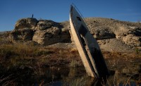 A man stands on a hill overlooking a formerly sunken boat standing upright into the air with its stern buried in the mud along the shoreline of Lake Mead at the Lake Mead National Recreation Area, Friday, Jan. 27, 2023, near Boulder City, Nev.