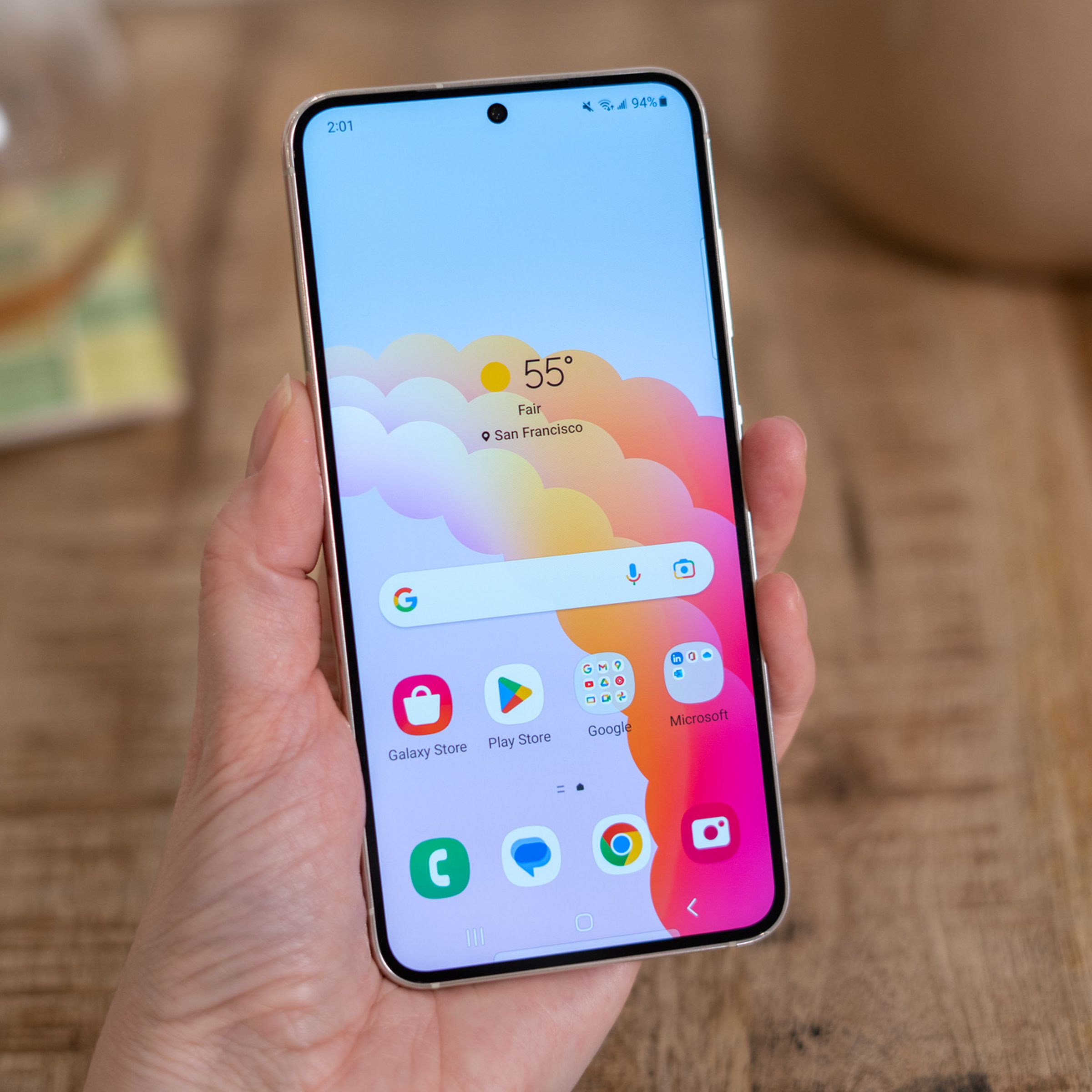 Samsung S23 in-hand showing homescreen with colorful wallpaper.