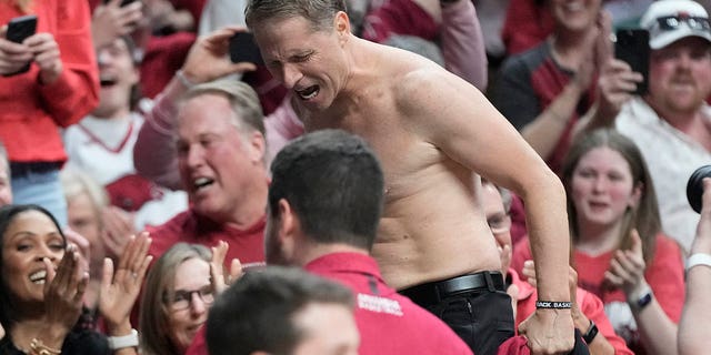 Arkansas head coach Eric Musselman reacts on the press table with his shirt off.