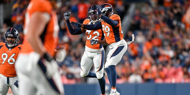 Safety Delarrin Turner-Yell #32 and cornerback Faion Hicks #29 of the Denver Broncos celebrate after a Turner-Yell sack on fourth down in the fourth quarter of a preseason NFL game against the Minnesota Vikings at Empower Field at Mile High on August 27, 2022 in Denver, Colorado.