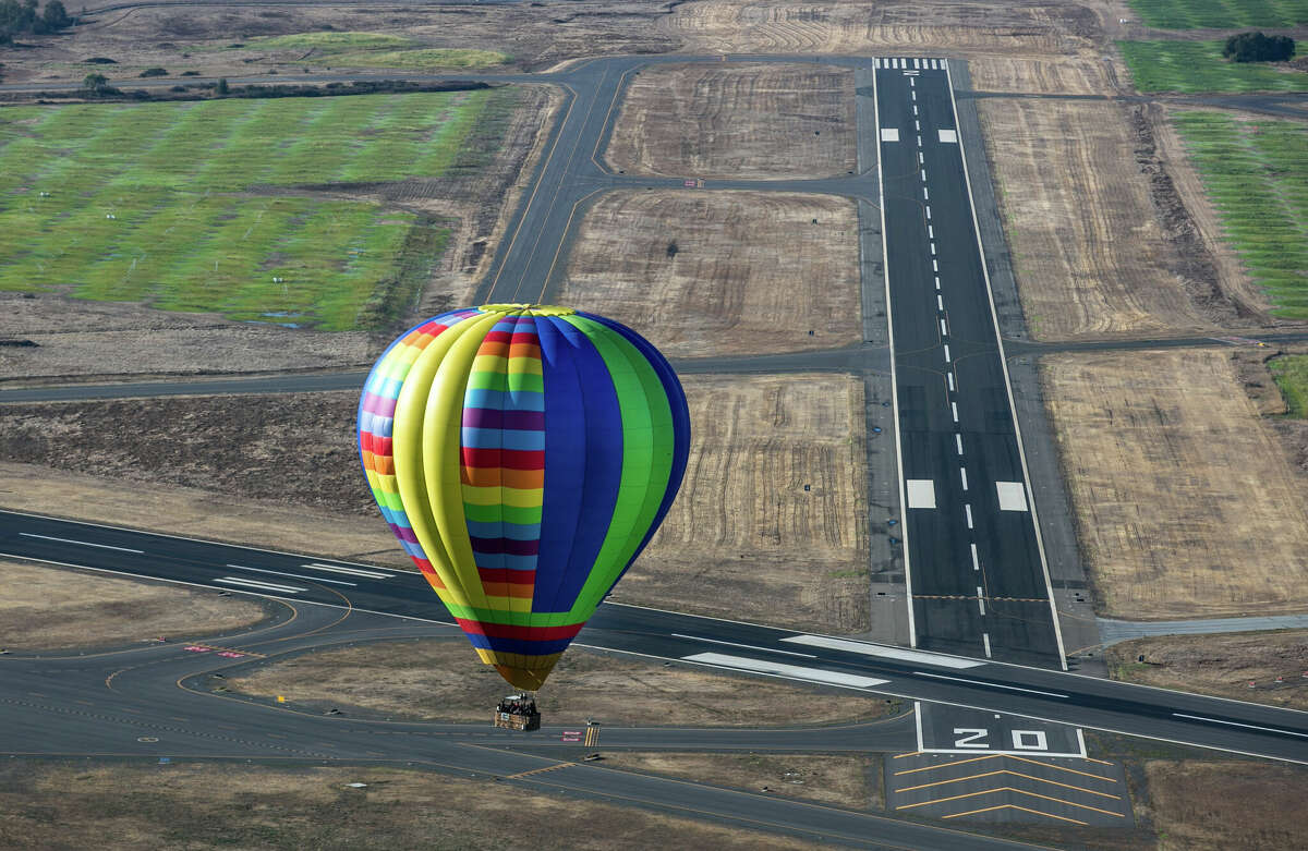 A hot air balloon floats over a jet runway near Charles M. Schulz Airport in this aerial photo taken Nov. 5, 2017, in Windsor, Calif.