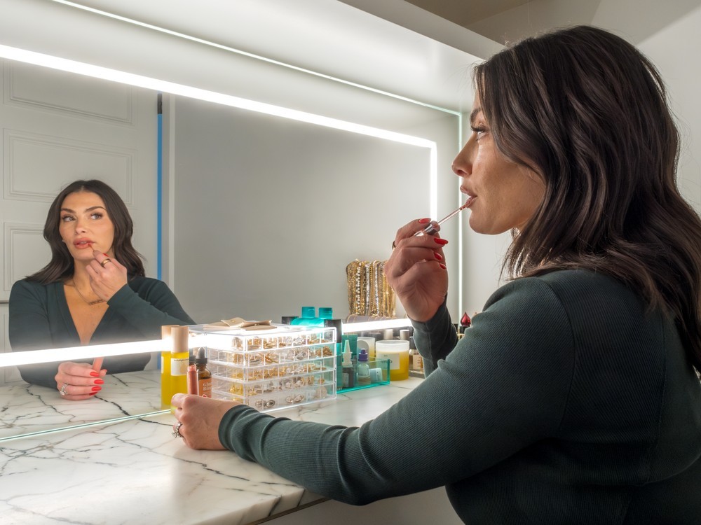 woman putting on lipstick in mirror
