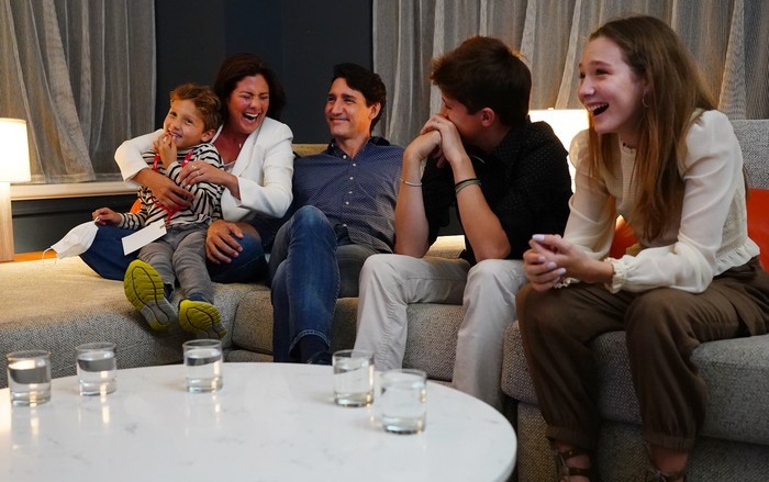 Sophie Gregoire Trudeau, Justin Trudeau and their three children are on a couch, laughing together.