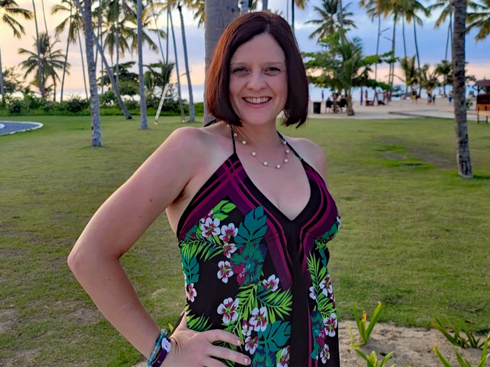 kari posing in front of a lawn full of palm trees in a tropical destination