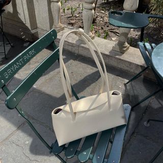 A Freja off-white shoulder bag on a park chair.