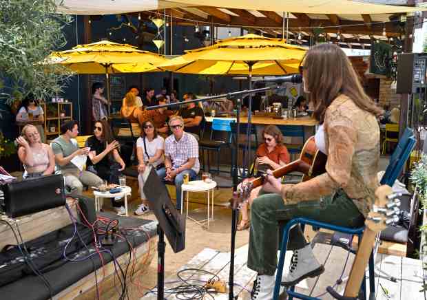 Visitors at Pour Co listen to Ashton Livesay perform during...