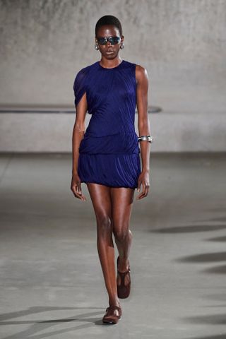 Model wearing a semi-sheer draped minidress on the runway at Tory Burch's spring/summer 2024 show during New York Fashion Week.