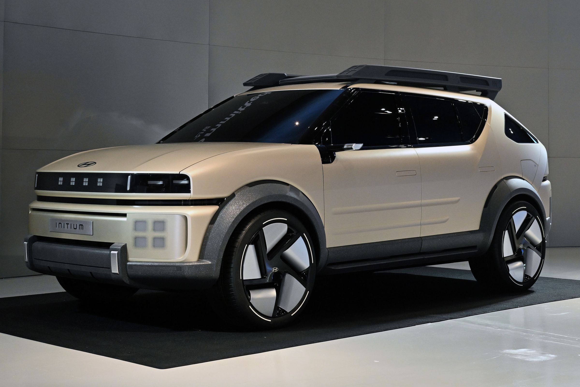 tan colored SUV on a show floor with black backdrop, four pixel lights on the grille.