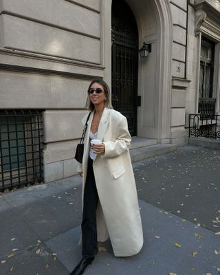 @hannahlewisstylist wearing a white maxi coat and black jeans in NYC