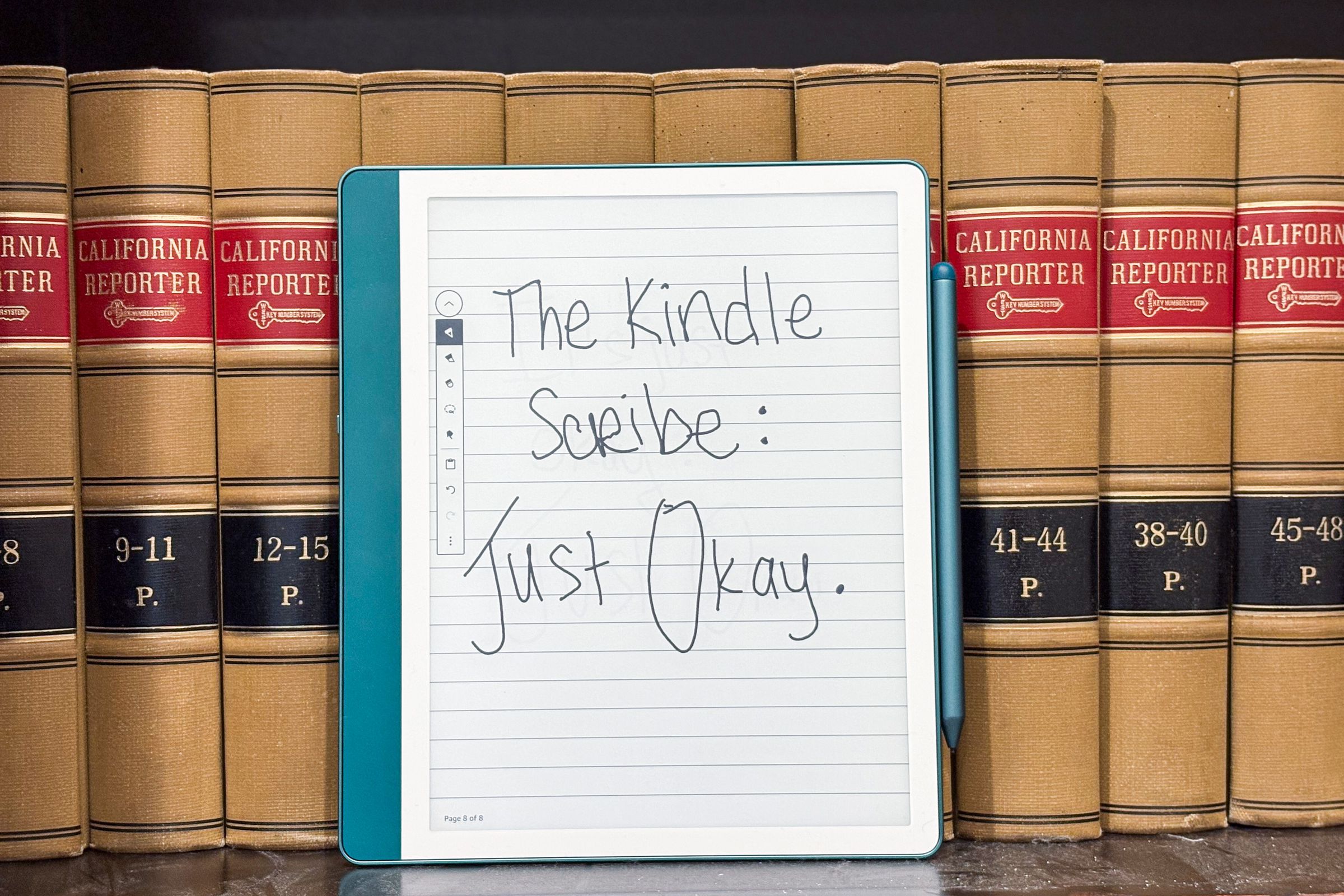 The Kindle Scribe resting against a bookshelf.