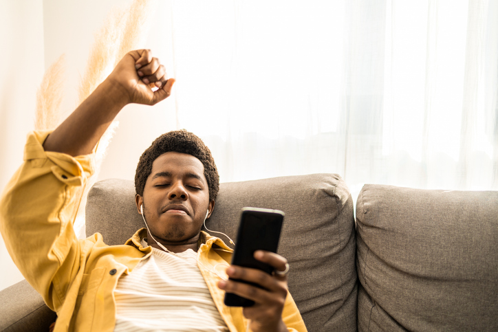 Portrait of young African American man listening music and smiling.