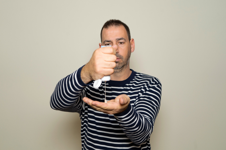 Bearded Hispanic man in his 40s wearing a striped sweater applying