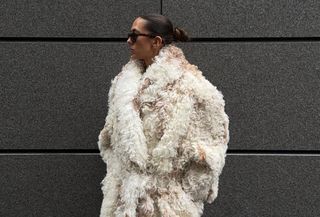 Woman wearing cream faux fur coat and matching ivory leather knee-high boots.
