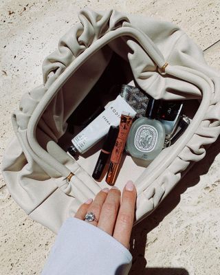A handbag with a Diptyque perfume in