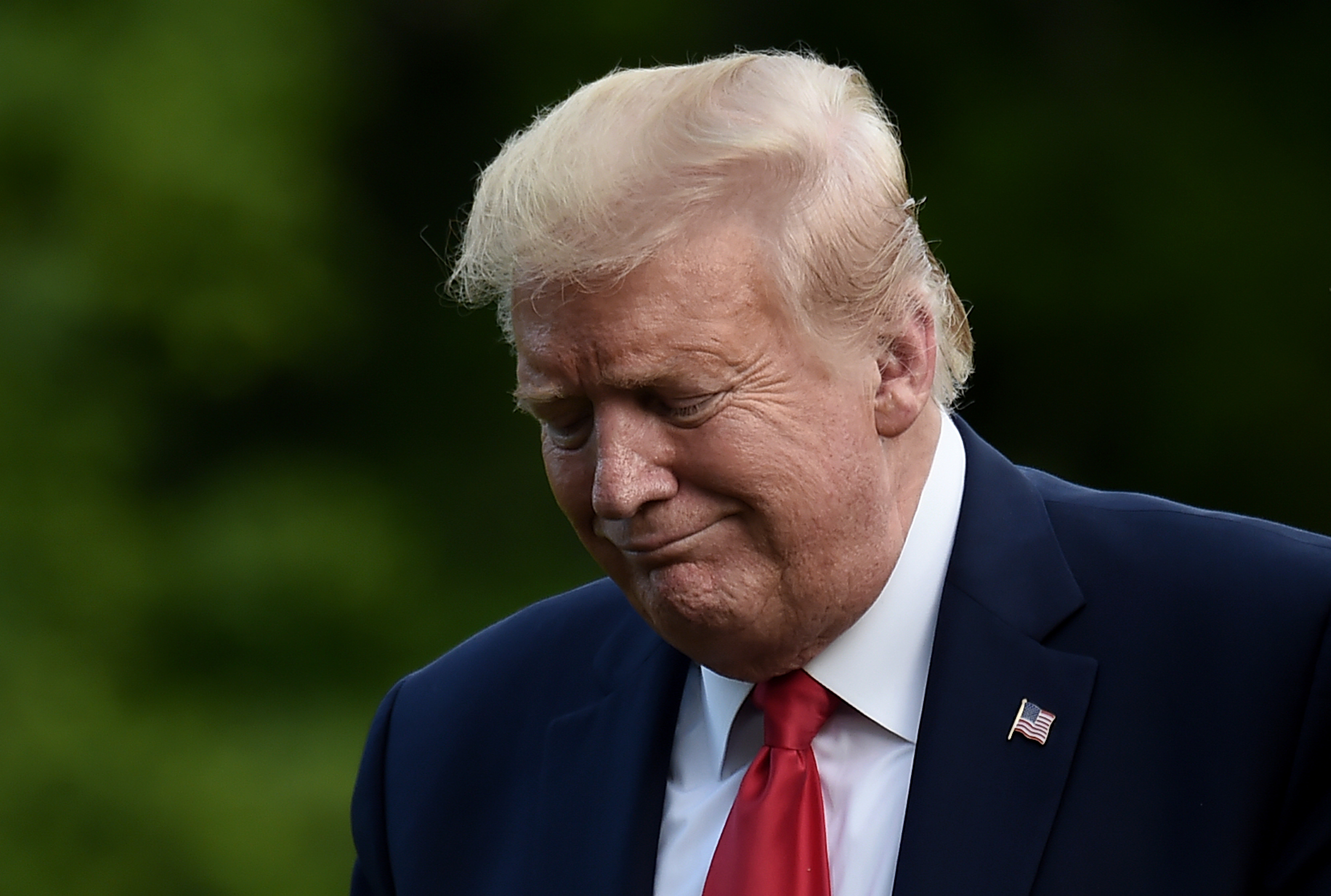 Donald Trump walks across the South Lawn of the White House with a pained expression
