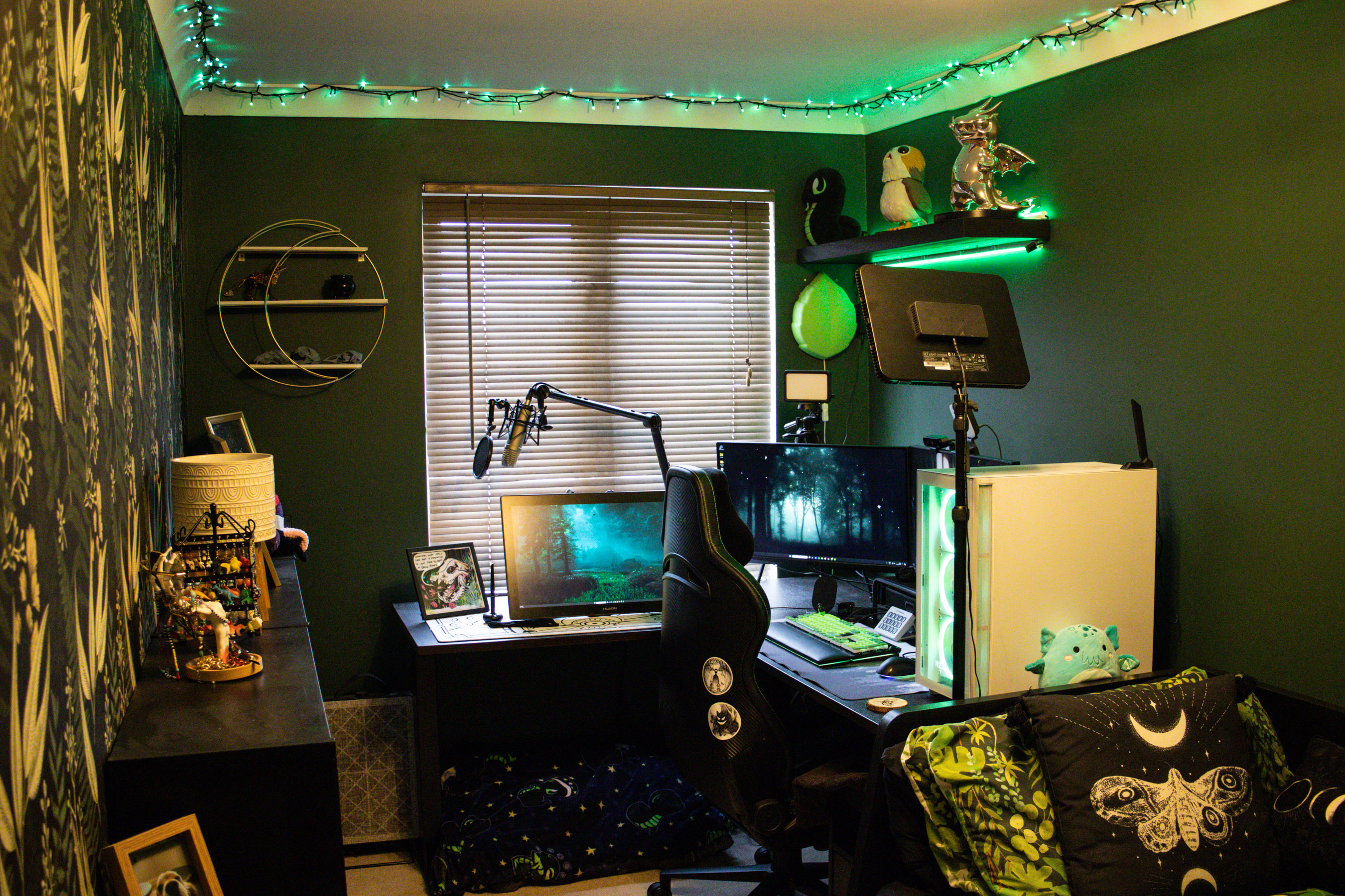 Home office with corner desk, green highlights, and a windows with blinds down.