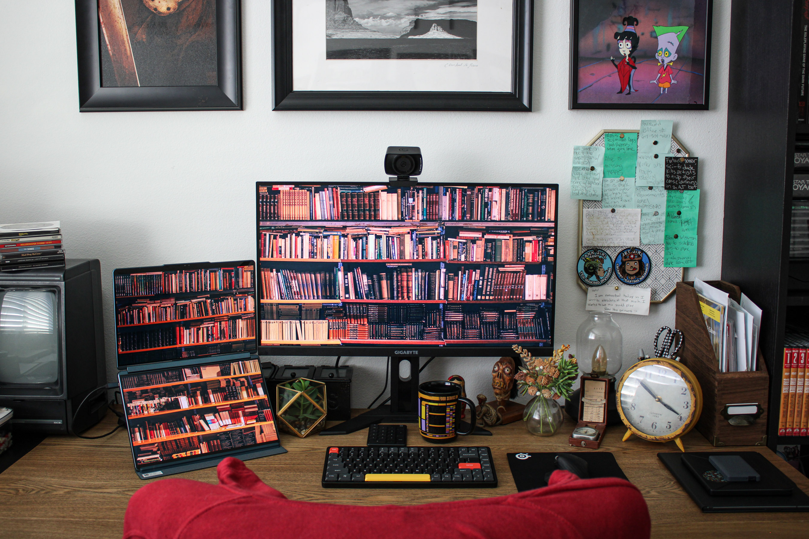 Straight head shot of desk with computers, photos of books on the displays.