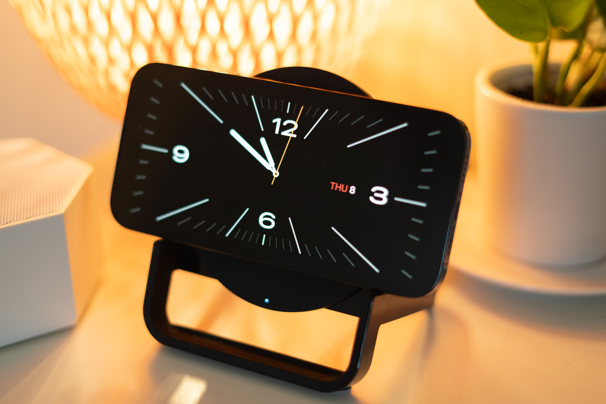 iPhone on a wireless charging stand showing clockface.