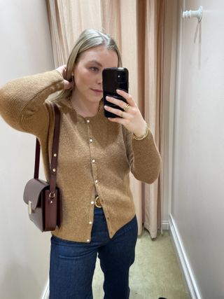 Woman wears camel cardigan, blue jeans and burgundy handbag