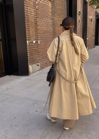 New York-based fashion influencer @trendingwithtinsley wearing a stylish spring outfit with a trench coat and sneakers.