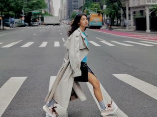 New York-based fashion influencer @himichelleli wearing a stylish spring outfit with a trench coat and sneakers.