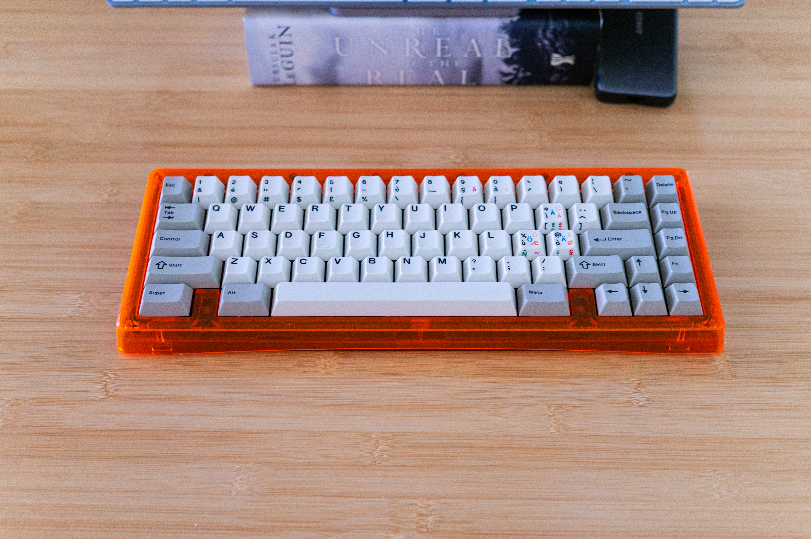 Bright orange keyboard on a bamboo desktop.