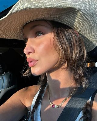 @bellahadid taking a selfie with chocolate brown hair and a cowboy hat
