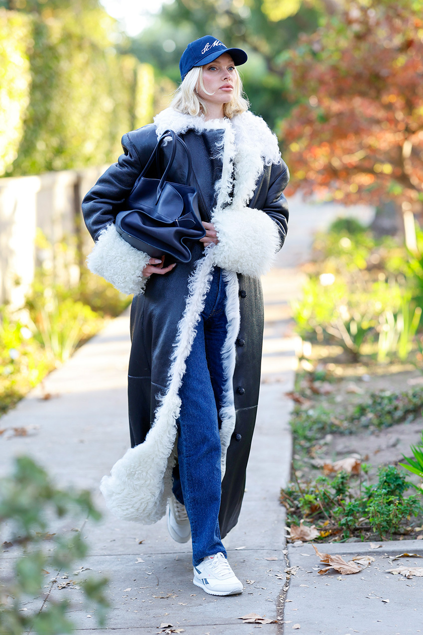 Elsa Hosk wearing a long leather coat, jeans, and sneakers