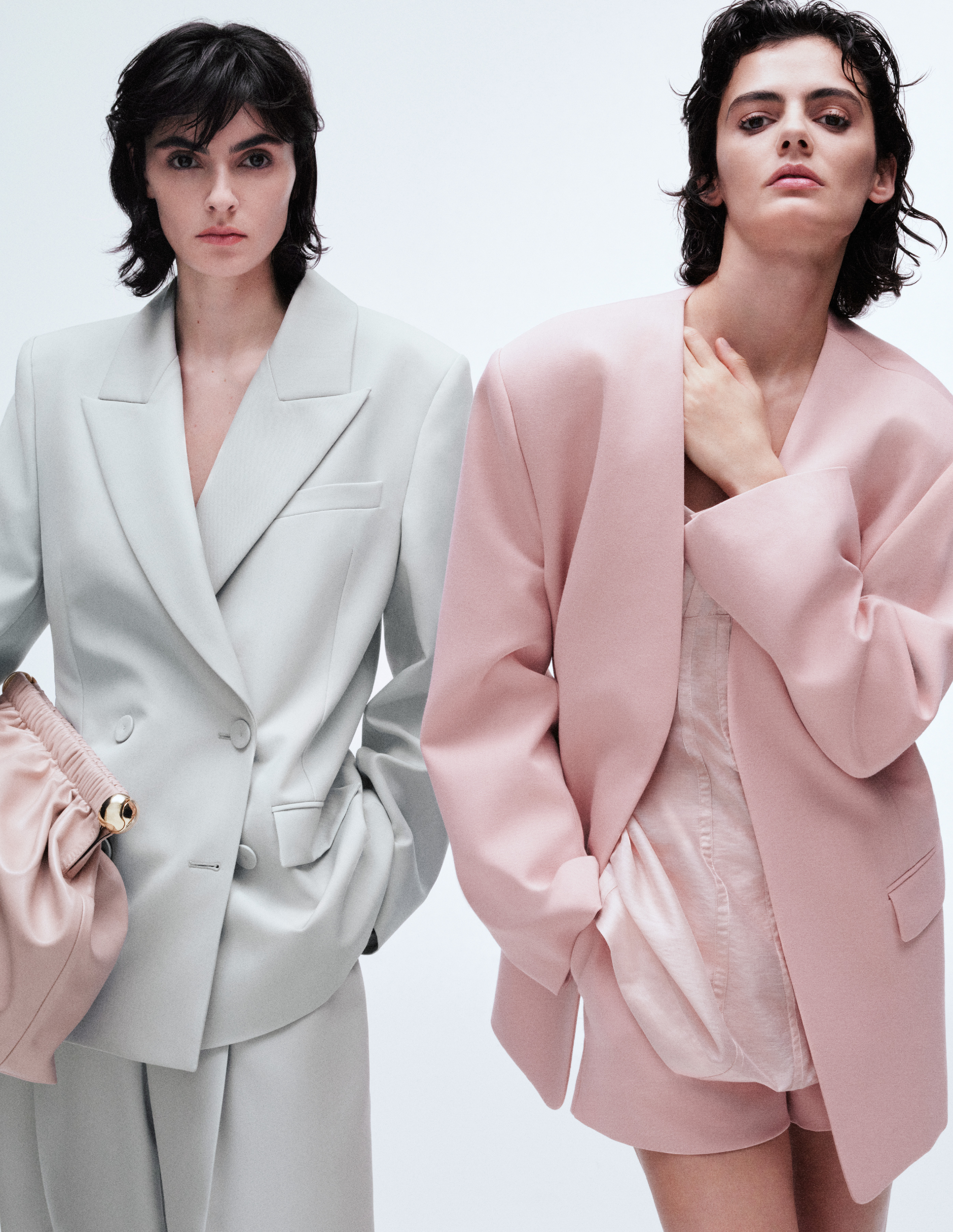Woman wears mint suit and pink handbag, second woman wears pink suit and pink tailored shorts