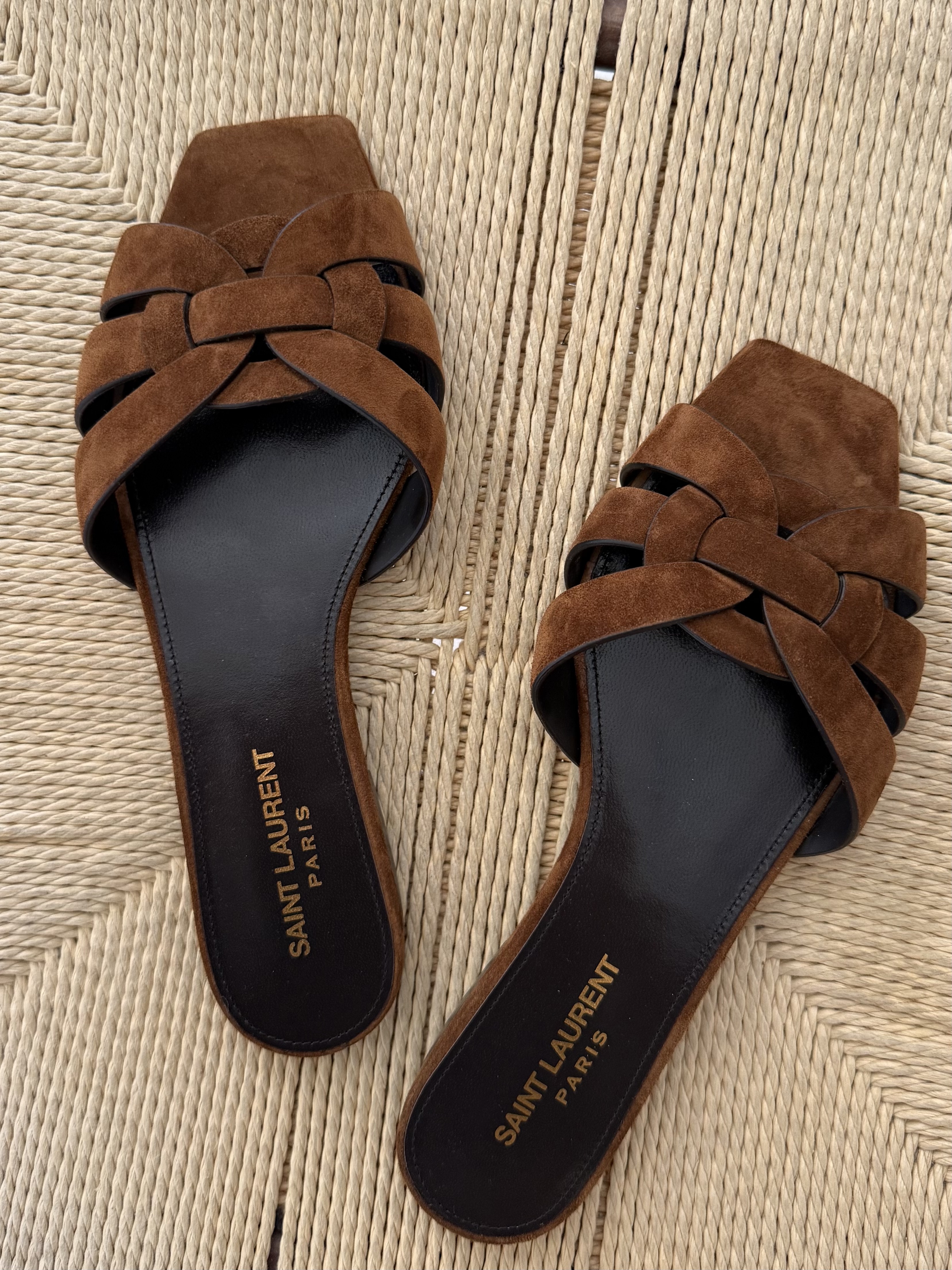 Pair of Saint Laurent Tribute Slide Sandals on raffia background.