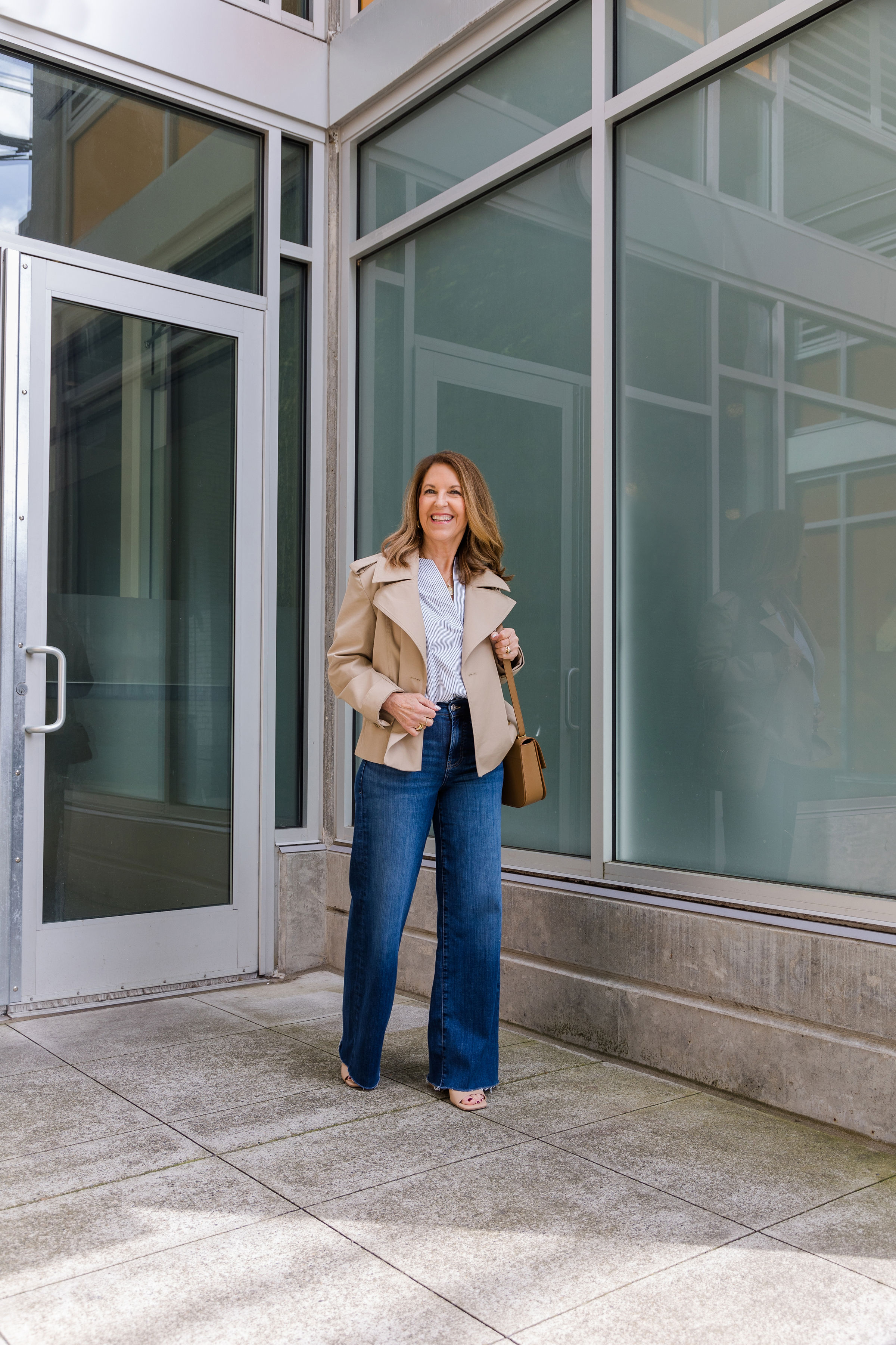 A former VIP Nordstrom stylist wearing a cropped trench, white tee, and dark-wash jeans.