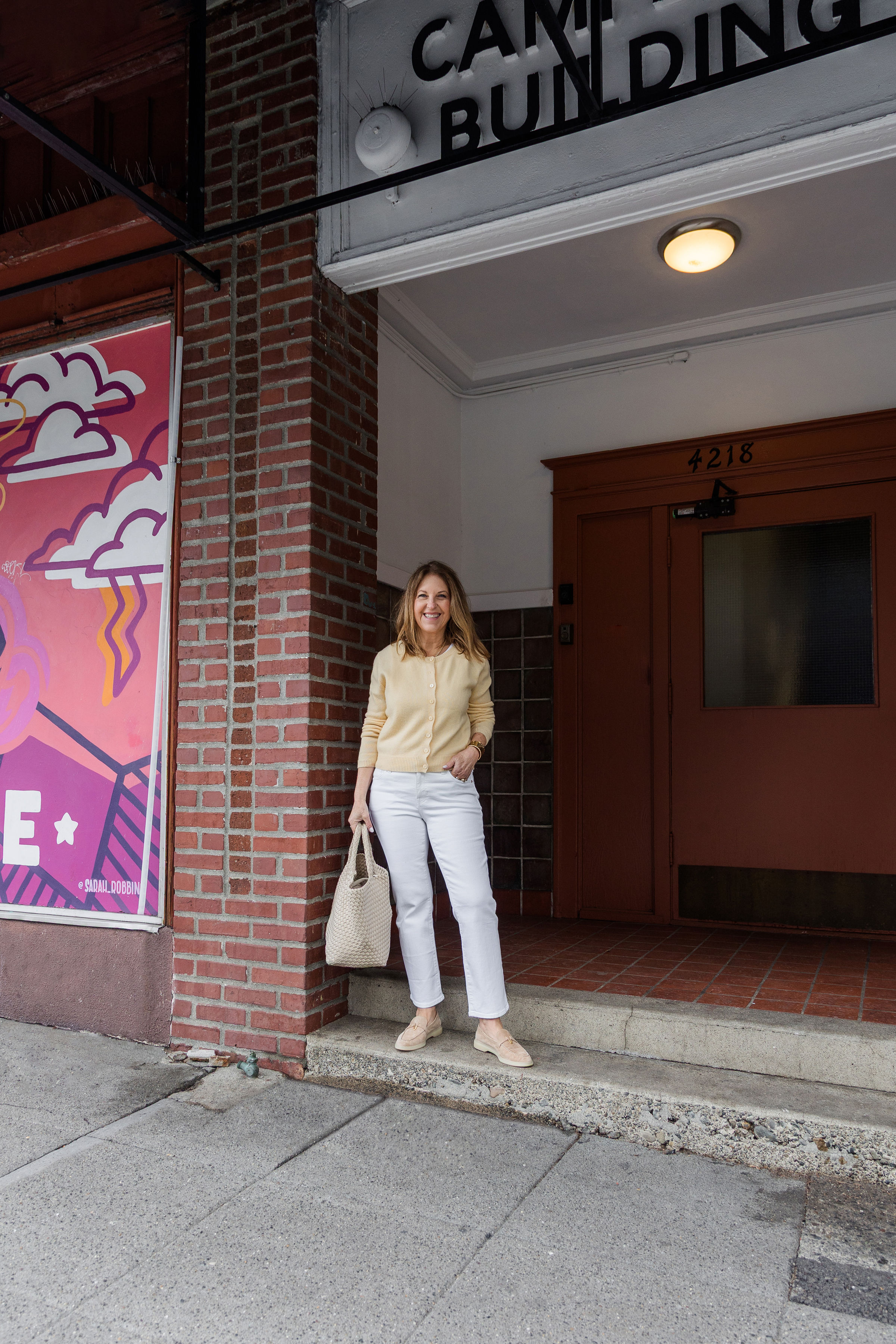 A former VIP Nordstrom stylist wearing a butter yellow cardigan, white jeans, and tan boat shoes.