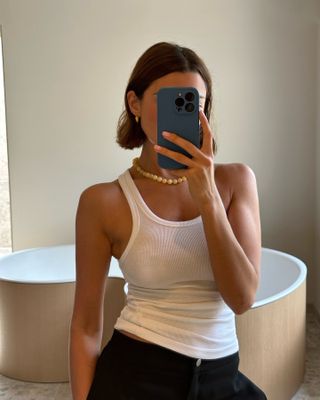 Woman in white tank top and black pants
