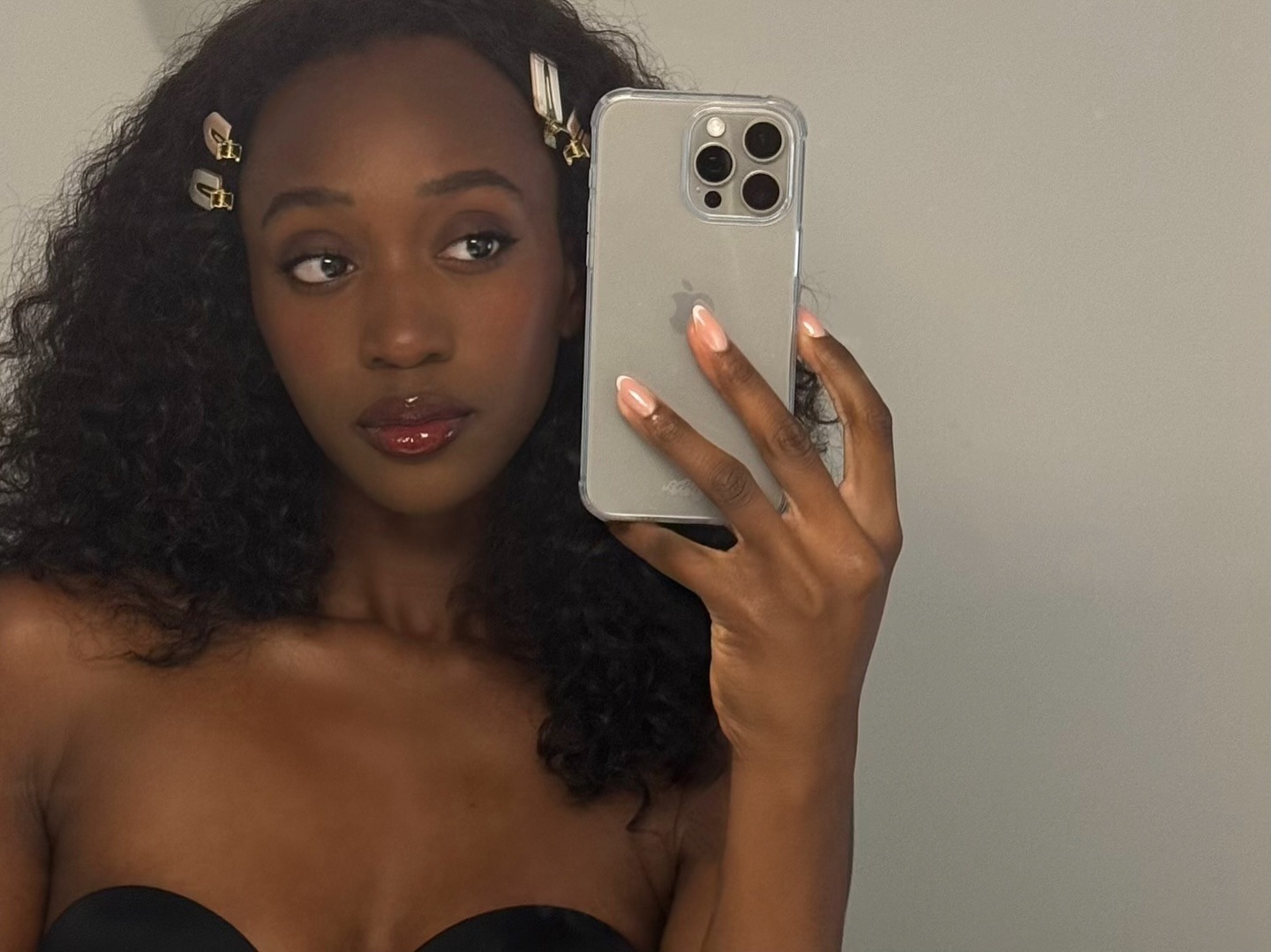 creator @emmanuellek_ taking a mirror selfie wearing soft makeup and lip gloss