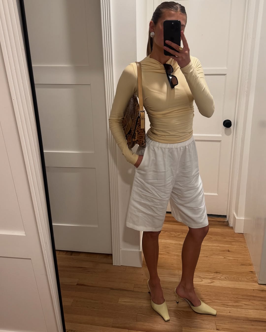 An influencer wearing a butter yellow top and white shorts.