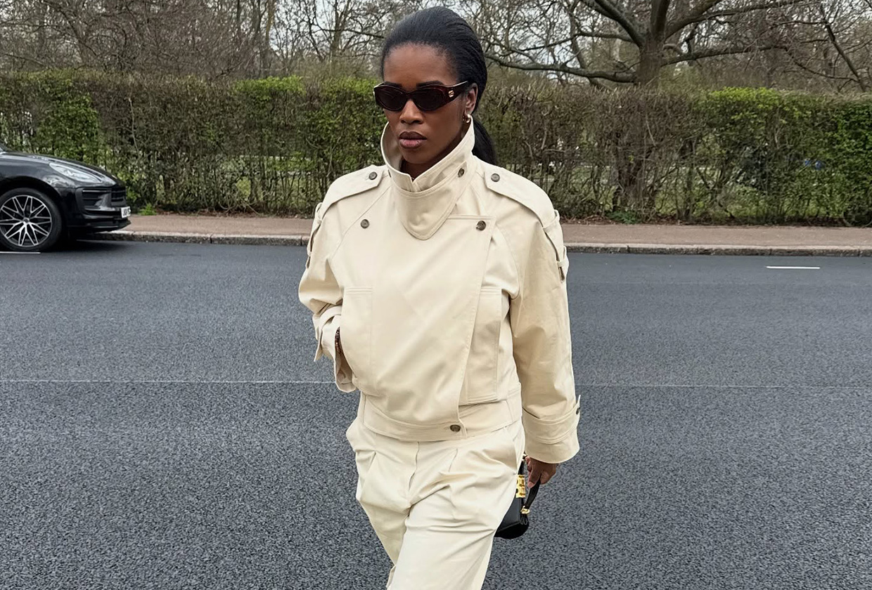 Marilyn wears a cropped trench coat and beige pants.