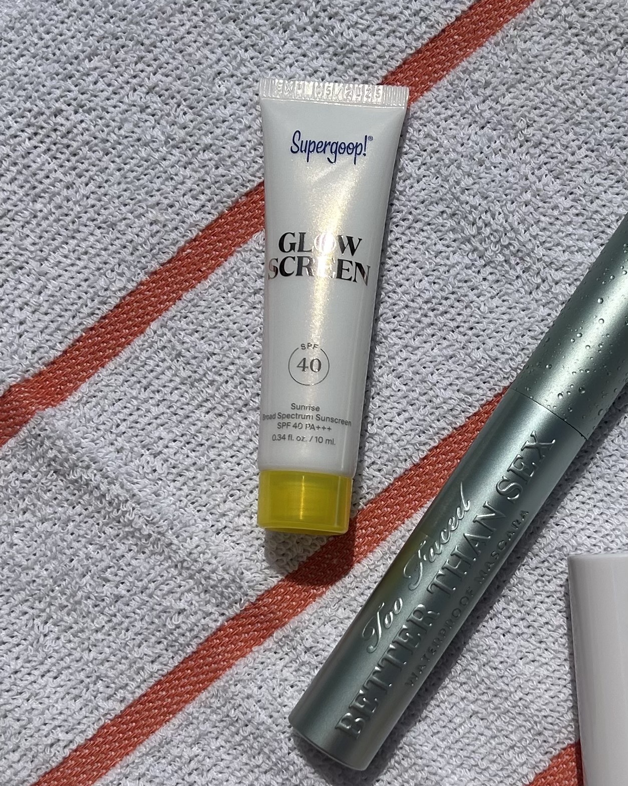 Supergoop Glowscreen lying on a beach towel.