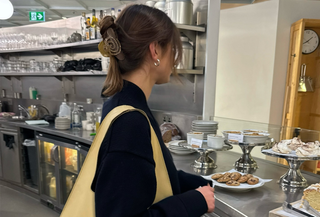 Poppy Almond wearing a black top with a butter yellow slouchy tote bag.