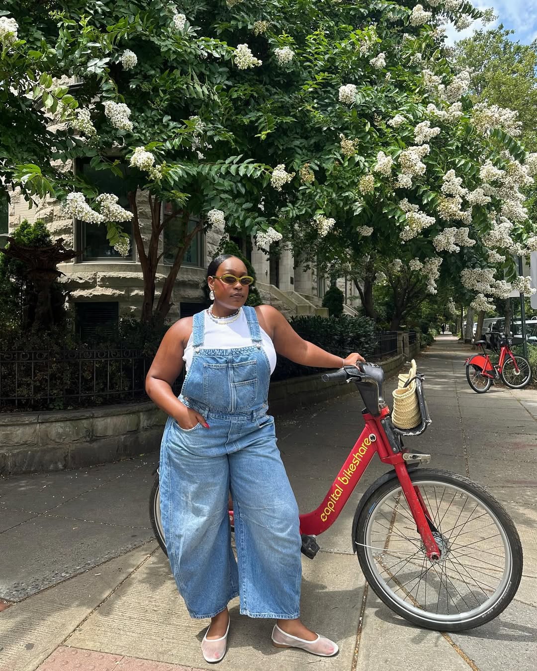 Woman wearing denim overalls with mesh ballet flats in a summer 2025 outfit.