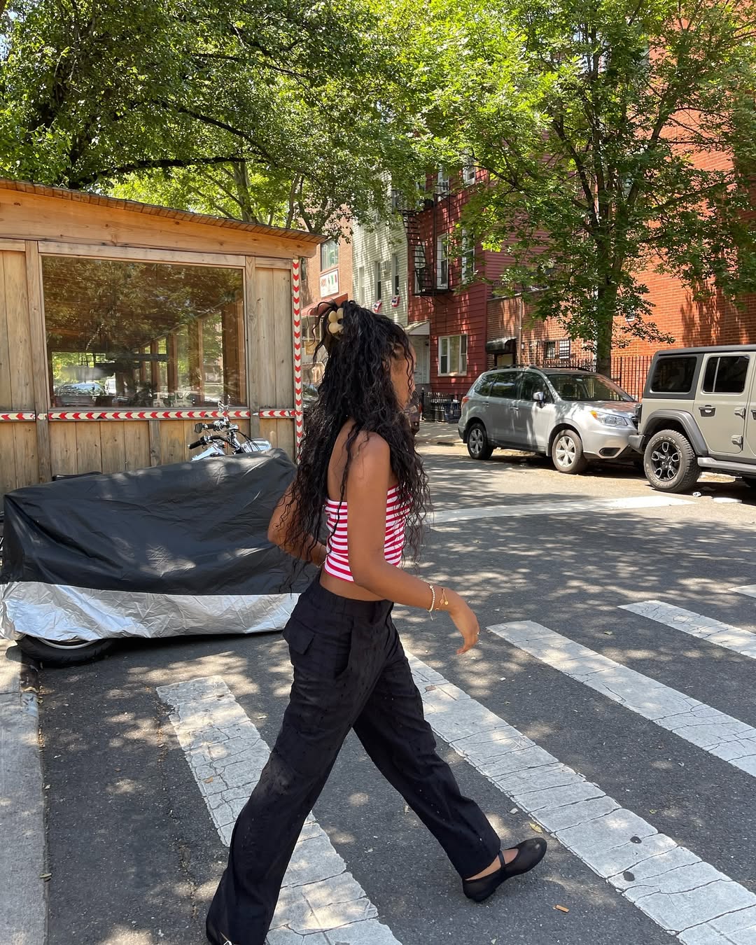 Woman wearing strapless top and black pants with ballet flats.