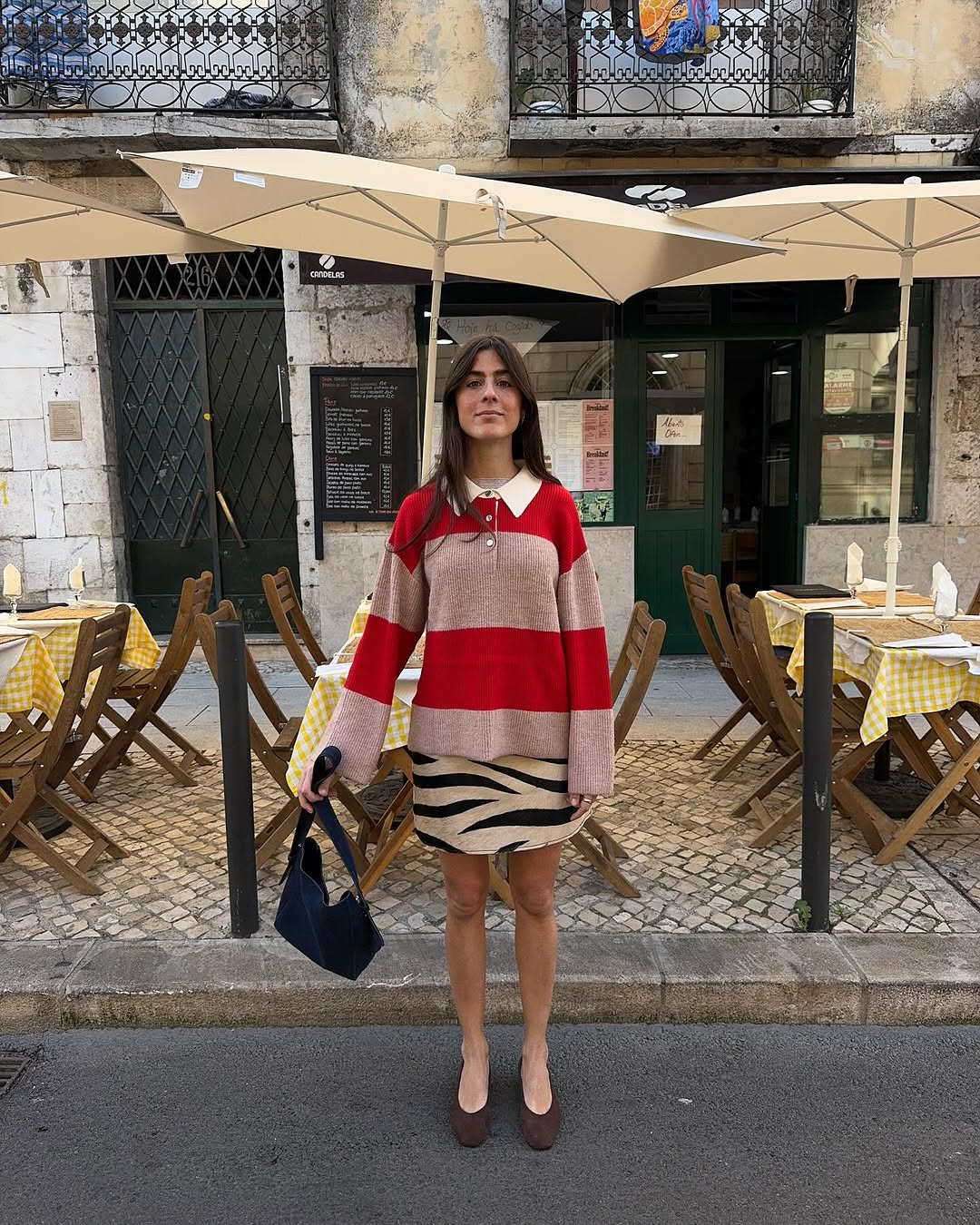 Woman wearing polo sweater with miniskirt and ballet flats in a summer 2025 outfit.