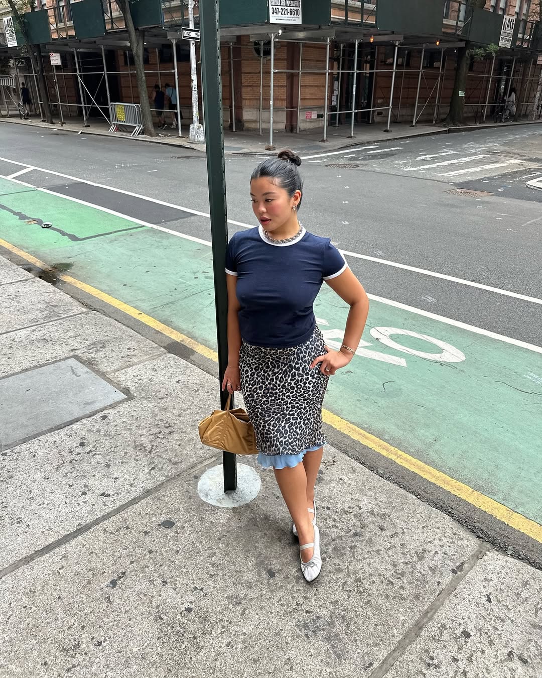 Woman wearing fitted t-shirt with midi skirt and ballet flats in a summer 2025 outfit.