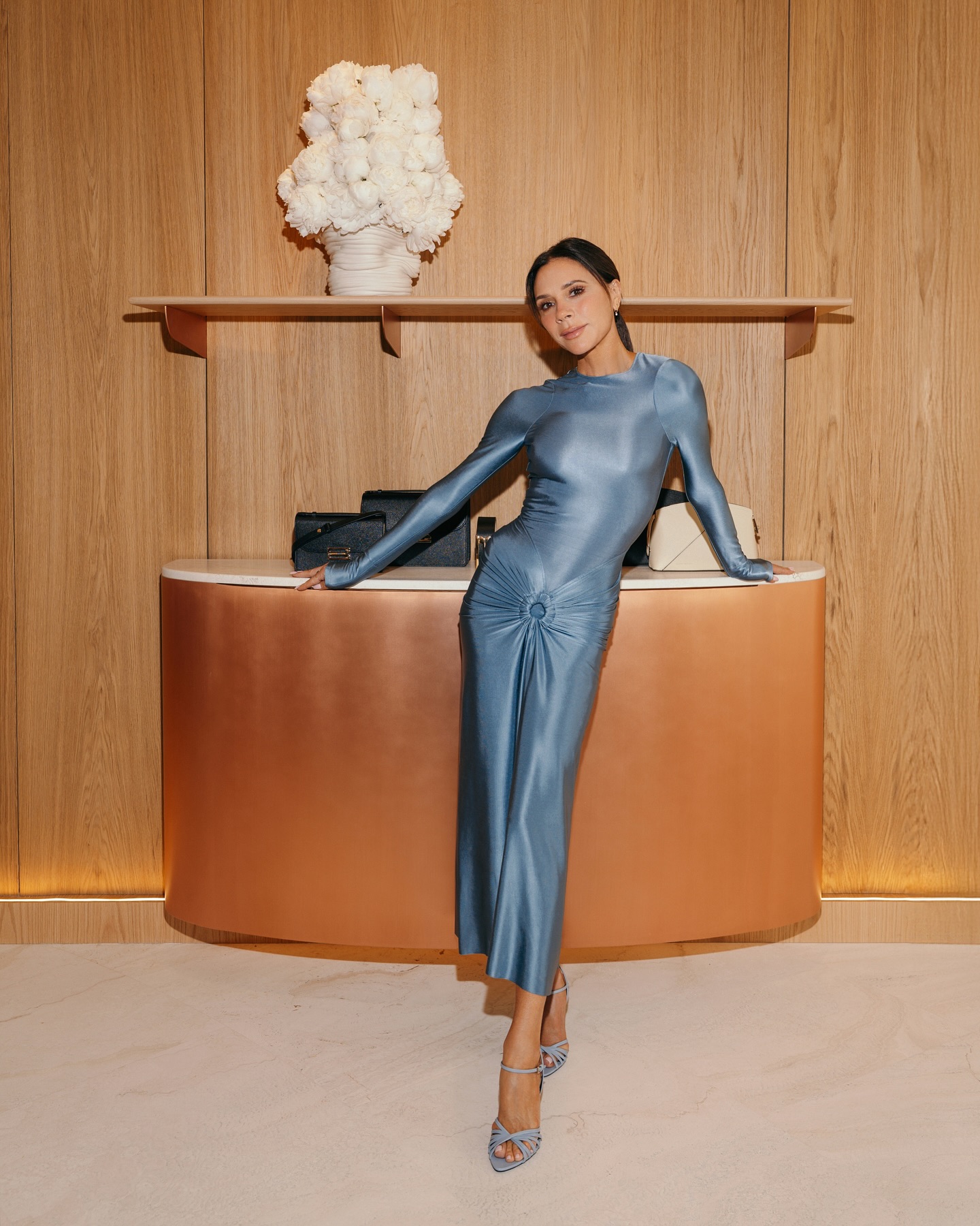 Victoria Beckham wears a blue dress with blue heels.