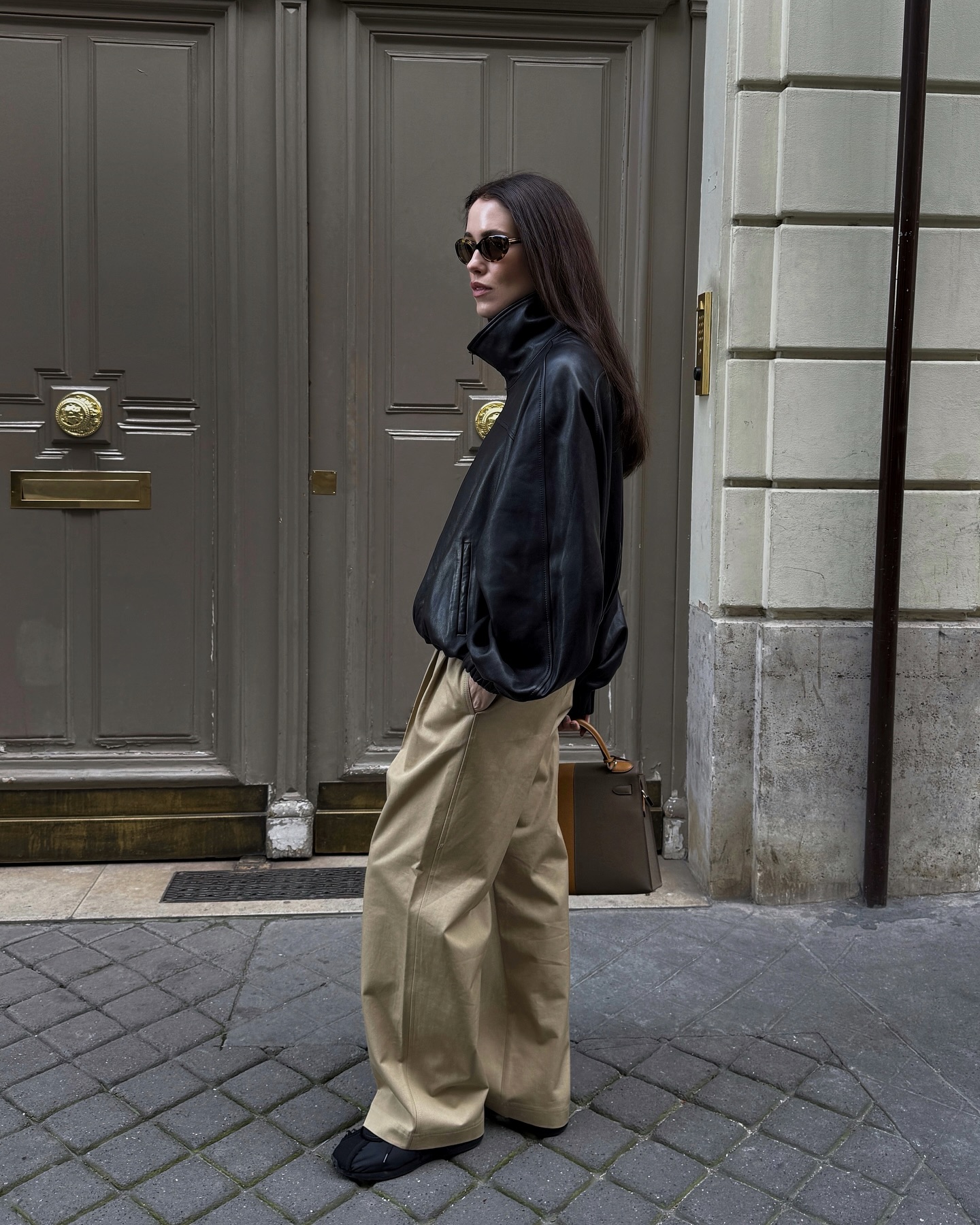 Annabel wears a leather jacket, sneakers, and chinos.