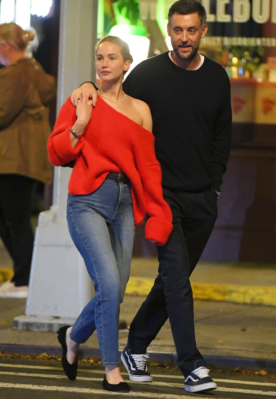 Jennifer Lawrence out walking in NYC with her husband wearing an off-the-shoulder red sweater, high-waisted jeans, and black suede ballet flats