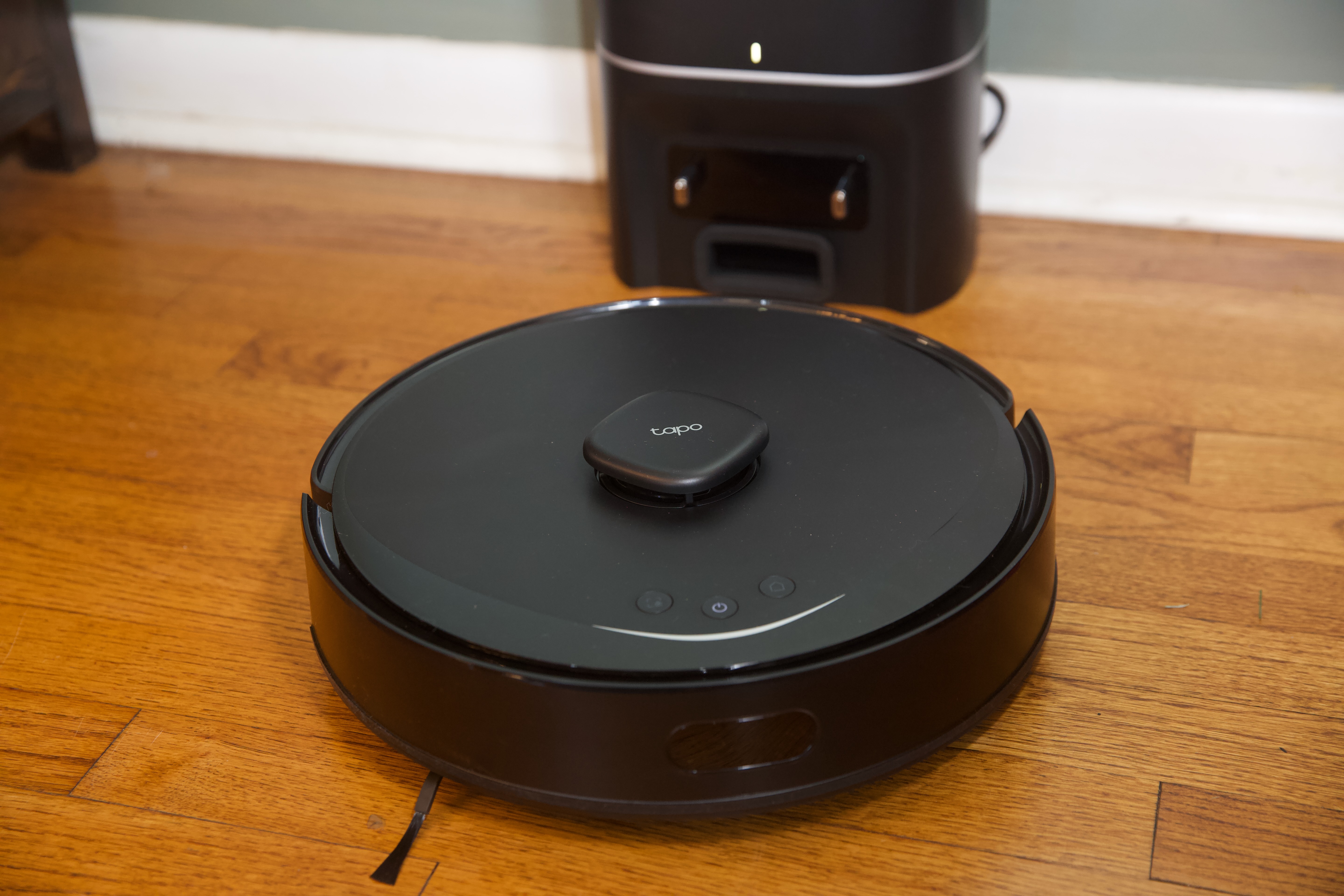 A black robot vacuum on a hardwood floor
