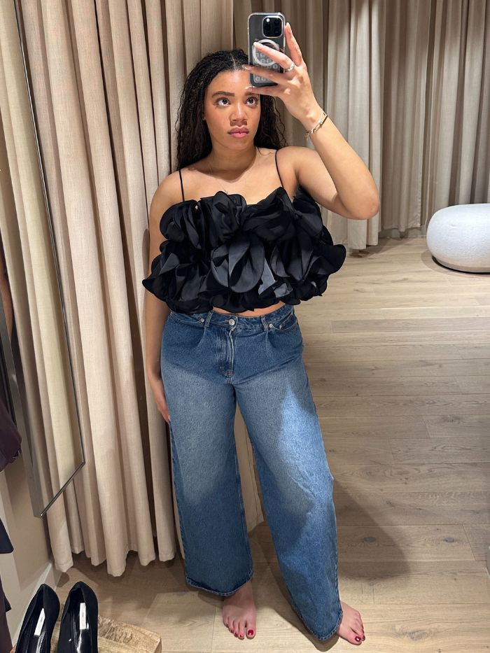 Woman wears black top and blue jeans