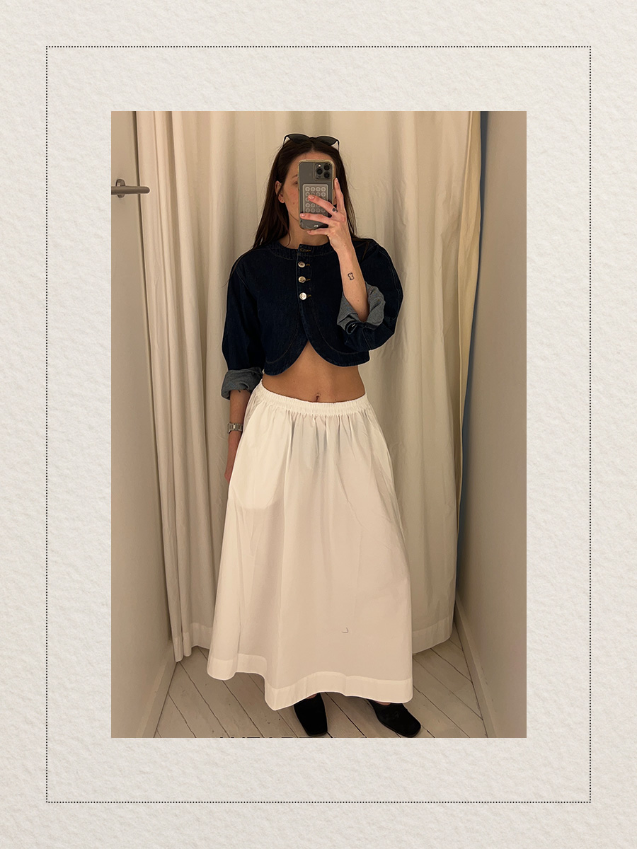 Eliza Huber at the new Aligne pop-up store in New York City's SoHo district trying on a denim cropped jacket and white skirt.